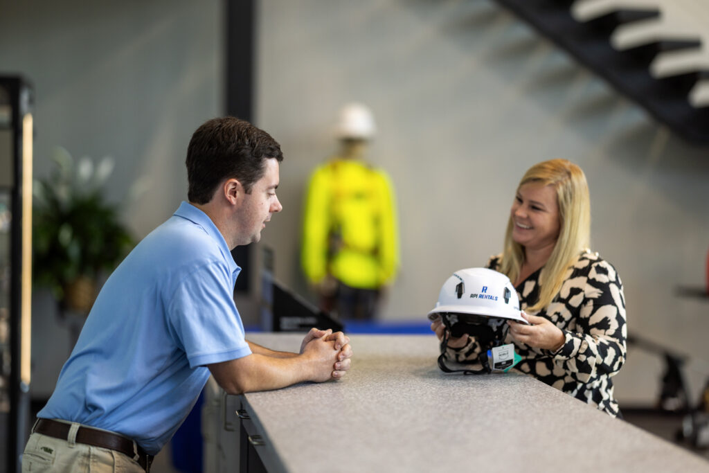 Man selling construction hard hat to woman